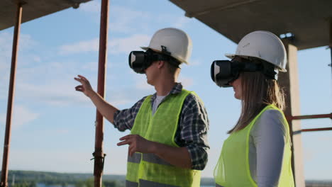 Two-contemporary-crew-workers-using-VR-to-visualize-projects-standing-in-unfinished-building-on-construction-site-copy-space
